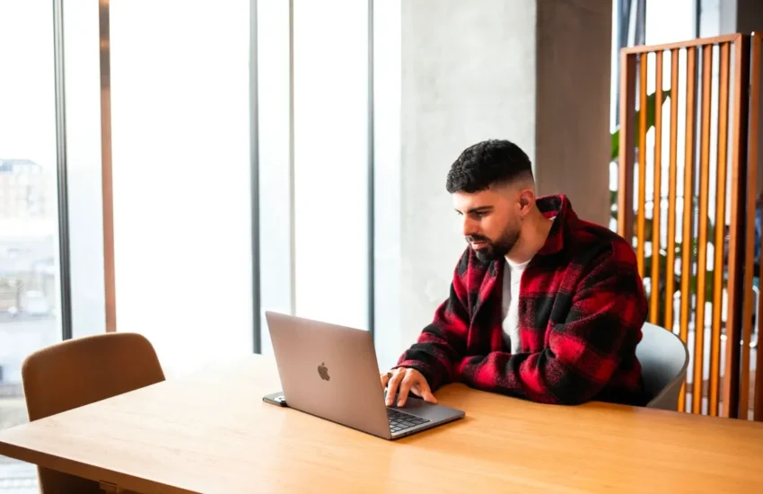 Mężczyzna pracuje na laptopie przy stole w jasnym pomieszczeniu
